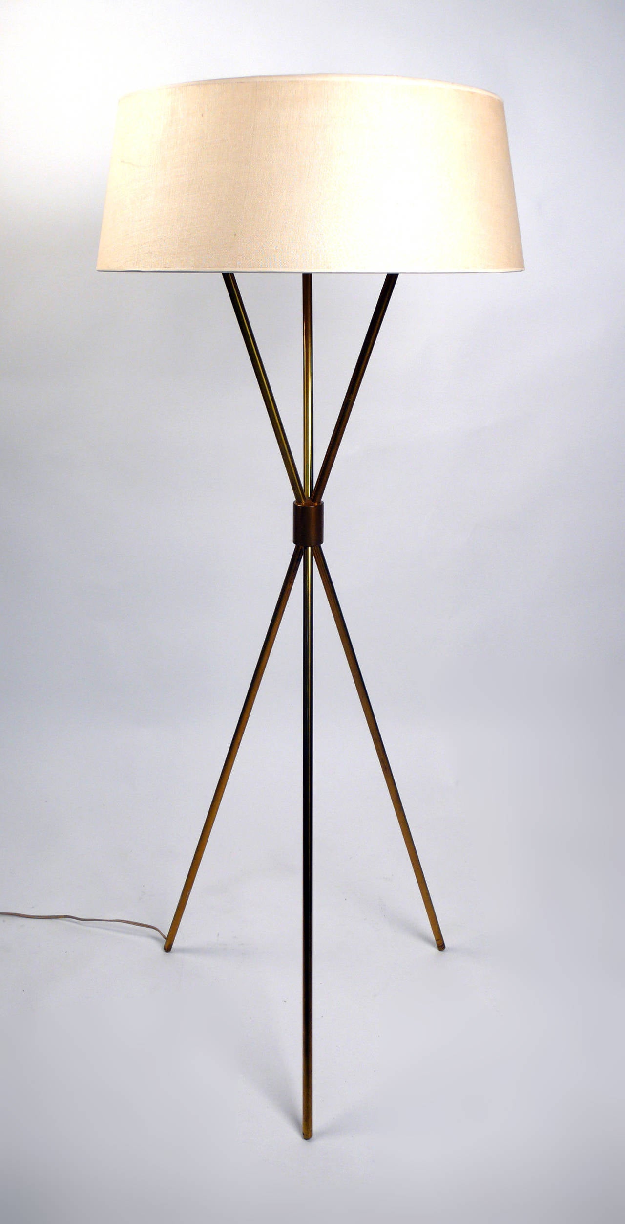 Early 1950s brass tripod floor lamp by T.H. Robsjohn-Gibbings for Hansen retains the original shade and functions as intended.