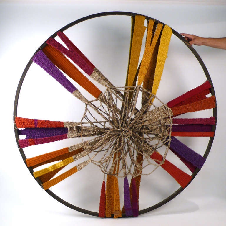 Almost five feet in diameter this massive fiber weaving includes quite a spectrum of vibrant 60's colors. The 'web' in the center is interwoven with brass decoration. Reminiscent of the dreamcatchers made by the Native American Ojibwe culture.