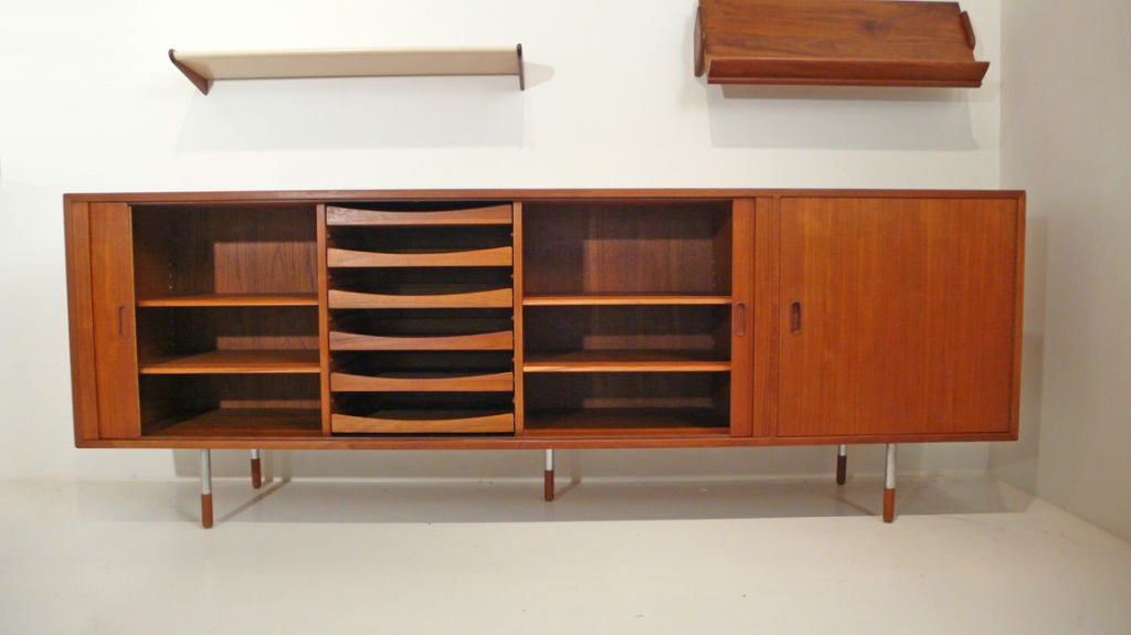 Arne Vodder for Sibast Danish Modern credenza in teak. The finely tamboured doors open to reveal a bank of drawers and adjustable shelving. The door on the right opens to reveal a dry bar. The 3 matching wall shelves can be reconfigured into any