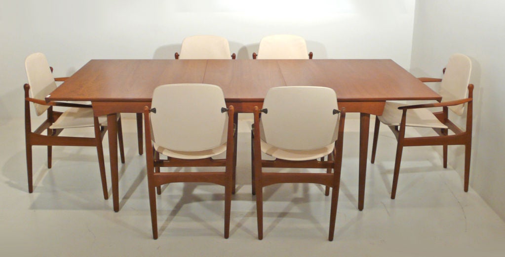 Danish Modern handcrafted teak dining table and chairs designed by world renowned cabinet maker Arne Vodder. Set includes four tilt back side chairs, two captains chairs and dining table with one leaf. Matching credenza available in a separate