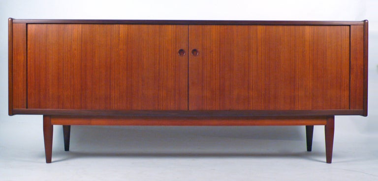 Danish Modern teak credenza with Tambour doors and adjustable shelving and three drawers. This piece is extremely well crafted and elegantly designed.