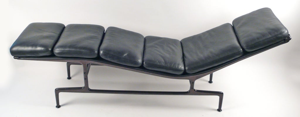 Iconic Charles Eames designed chaise lounge in black leather with dark Eggplant frame. This example dates from the late 20th Century. Extra cushions not included.