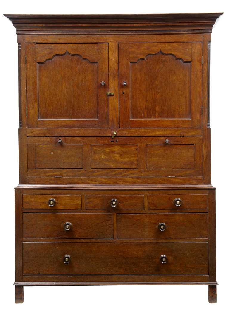 Good quality oak cupboard. Splits in two parts, top section comprising of double oak doors which open out to reveal small shelf, underneath a drop down hatch door with further cupboard space. Bottom section consists of three short drawers over two