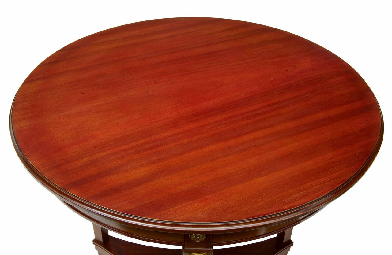 Empire style mahogany table, circa 1900 

Rich circular mahogany top, Egyptian ormolu mounts to the legs. 

Standing on 3 legs, with uniting shelf near the feet.

Height: 31