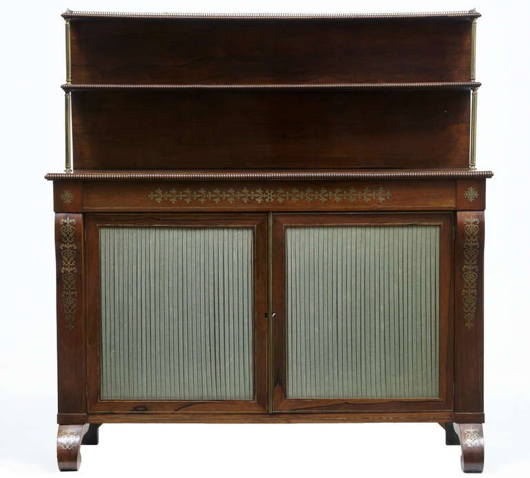 Excellent quality chiffonier, brass inlaid elements to the central cartouche and feet. 

Two shelves to top supported by brass pillars with small gallery on top tier.

Pleated silk doors open to reveal two shelves.