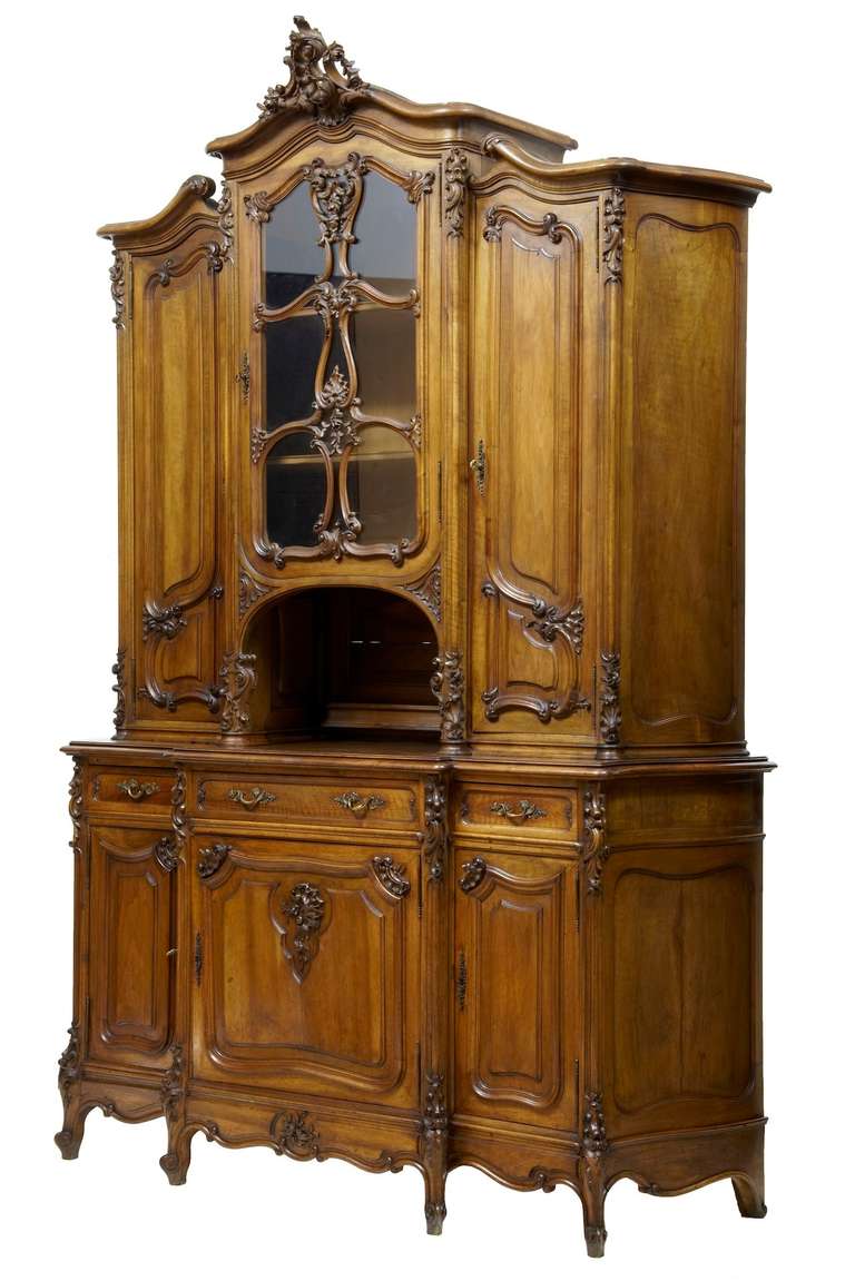 Stunning Rococo Influenced French Walnut Vitrine Circa 1880.

Comprising Of 2 Sections, The Top Half Features A Glass Fronted Cabinet Adorned With Carved Florals And Swags, Below Which Is A Open Cupboard. Flanked Either Side By A Cupboard