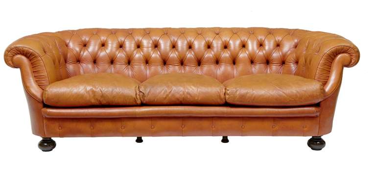 Super quality tan leather chesterfield suite, circa 1970.<br />
<br />
Very comfortable and excellent quality leather button back rollover arm chesterfield sofa and two armchairs. in excellent condition.<br />
<br />
Standing on turned feet.<br