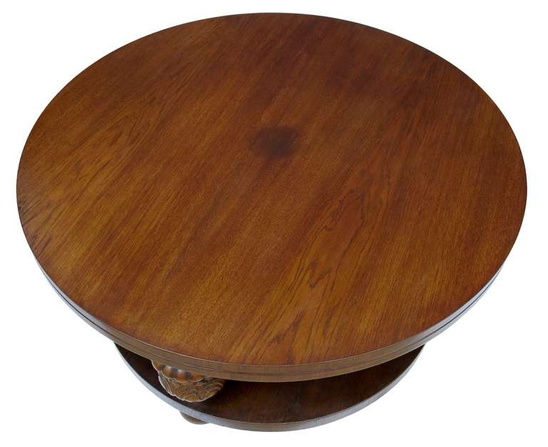 Carved oak coffee table, circa 1925. Double edged round top, supported by four carved baluster legs, followed by a further shelf. Standing on bun feet.