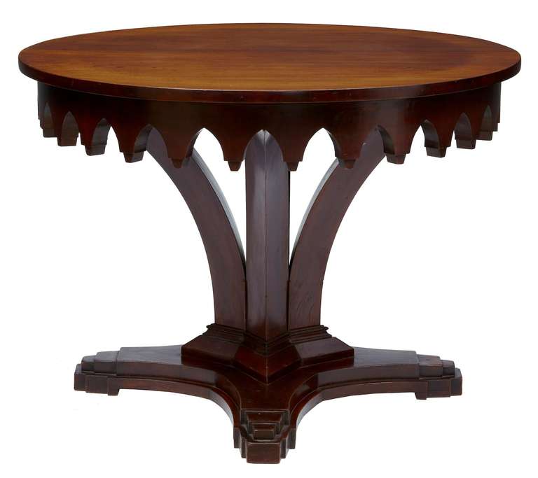 Unusual Art Deco center table, circa 1920. With a strong Gothic influence in the carved frieze. Four fluted tapered supports lead down to unit at the quadriform typical Art Deco base, surrounding the tapered obelisk in the center.

Measures: