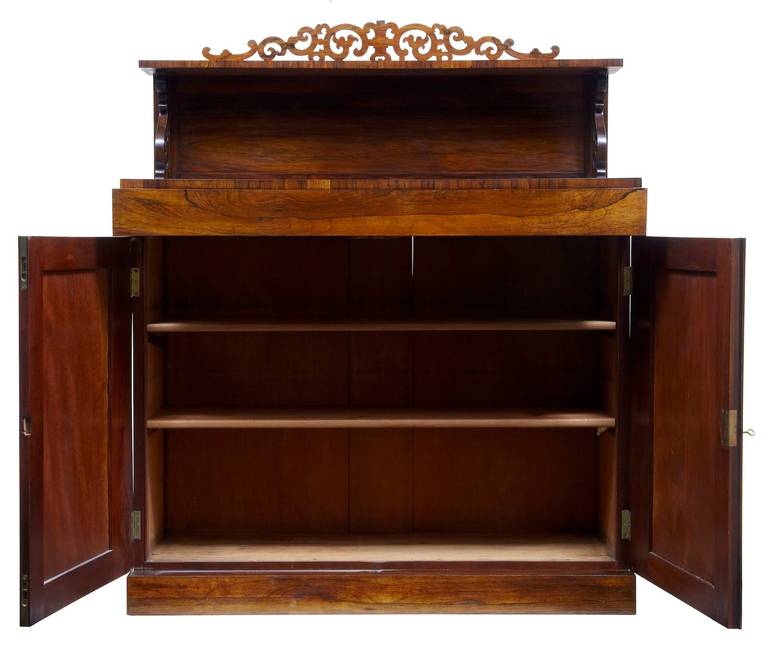 Fine quality chiffonier, circa 1820. 

Two-tier, top tier complemented by pierced gallery edge, carved scrolls leading down to the main surface. Double doors open to reveal two shelves.

Measures: Height: 54