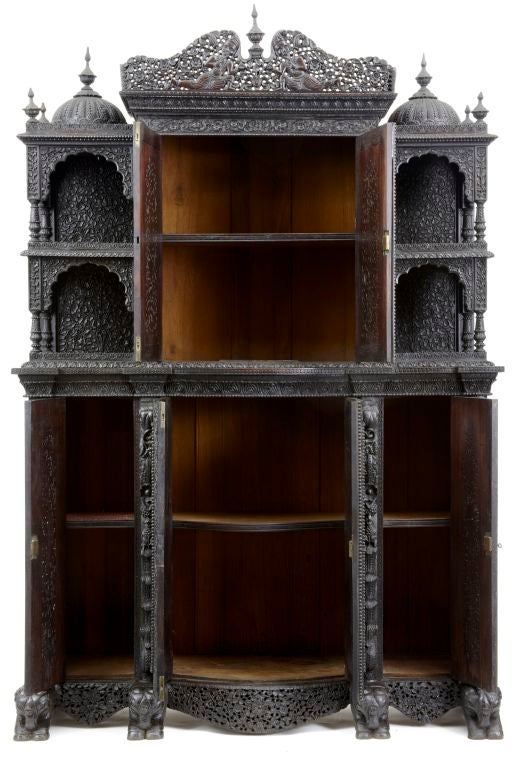 19TH CENTURY ANGLO INDIAN BREAKFRONT CABINET WITH CARVED DESIGN OVER SIX DOORS OF FLORAL, ANIMALS, MEN AND BUILDINGS SHOWN OVER THE WHOLE CABINET.  <br />
<br />
THE CABINET IS HELD UP ON FOUR CARVED ELEPHANTS.<br />
  <br />
TOTALLY 100%