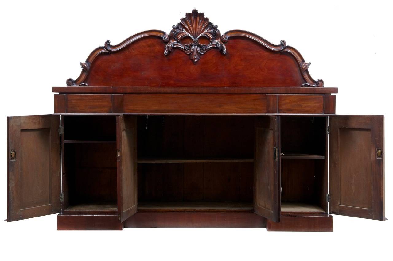 Good quality mahogany sideboard, circa 1835. 

Lovely rich color. Main feature is the deeply carved stylised floral/shell central carving. 

Two parts. 

Three drawers above a double door cupboard containing a single drawer, flanked either
