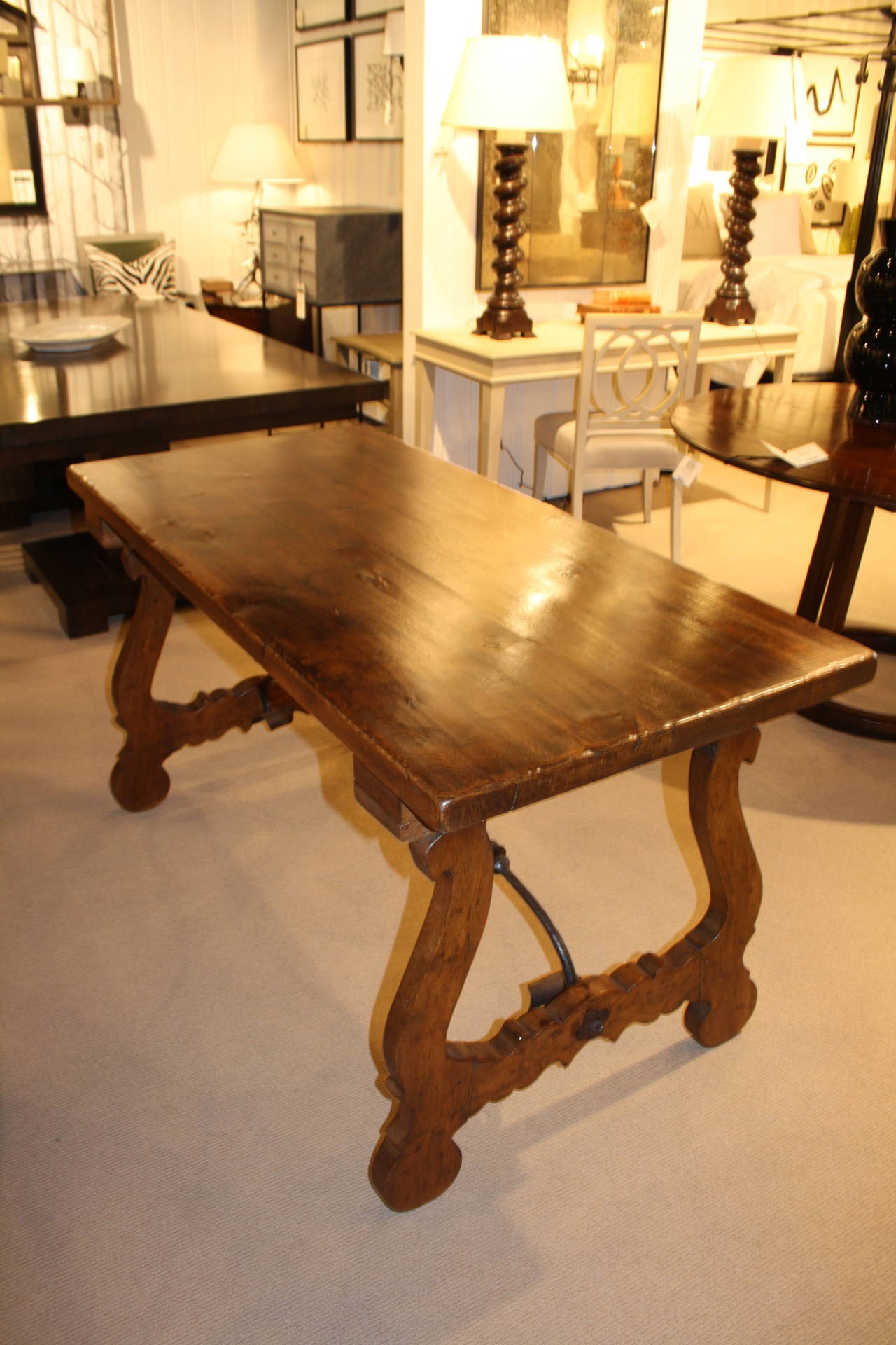 Mid-20th century Spanish oak table with two decorative iron stretchers and carved legs.