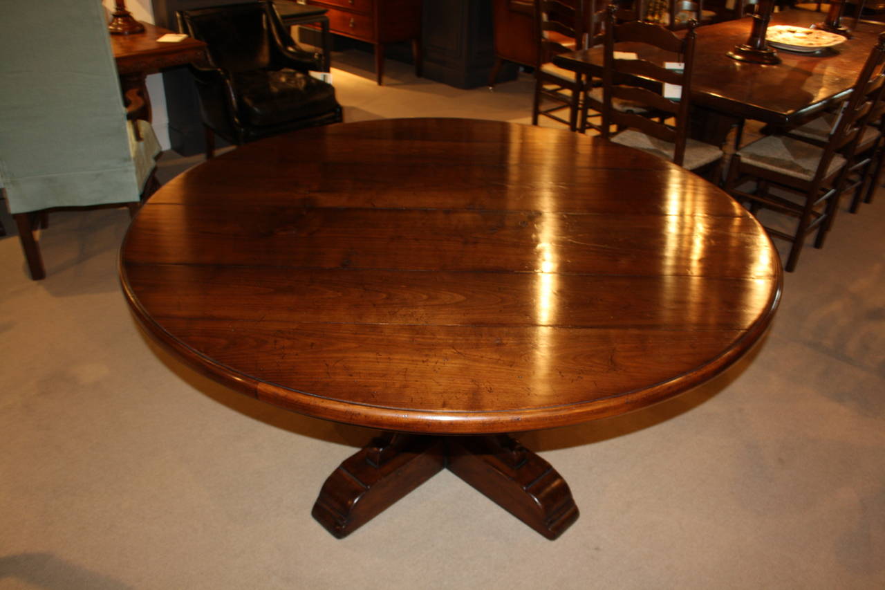 Round pedestal table in medium cherry. Solid base with decorative carving. Weathered top.