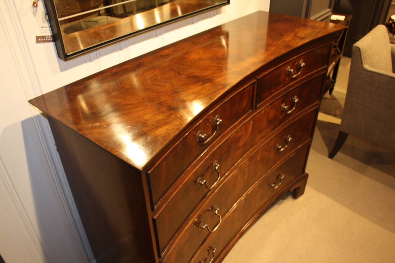 Georgian style concave chest in faded mahogany with ornately carved feet. This chest has five draws each with a lock and eight brass handles. Keys are included.