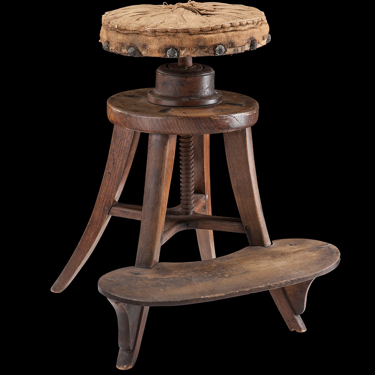 Early painter's stool, with adjustable seat heigh. Upholstered in burlap, stuffed with hay and finished with large brass studs.

Made in France circa 1880.