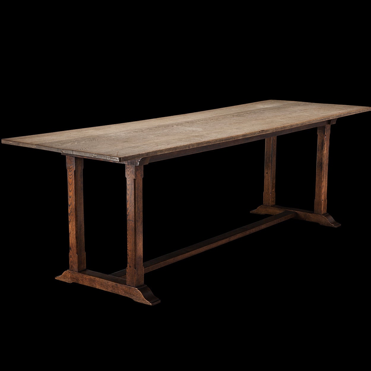 Solid oak table with low stretcher and twin pillar supports.

Made by Heals of London circa 1920.