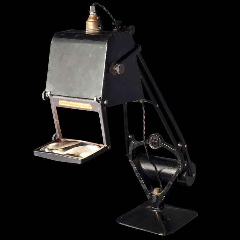 Articulating, weighted iron desk lamp with retractable magnifying lens 
  