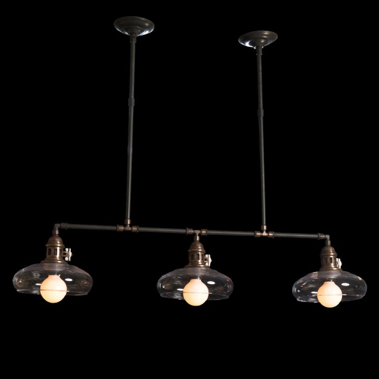 Industrial ceiling fixture with three rounded glass shades, connected with pipe fittings