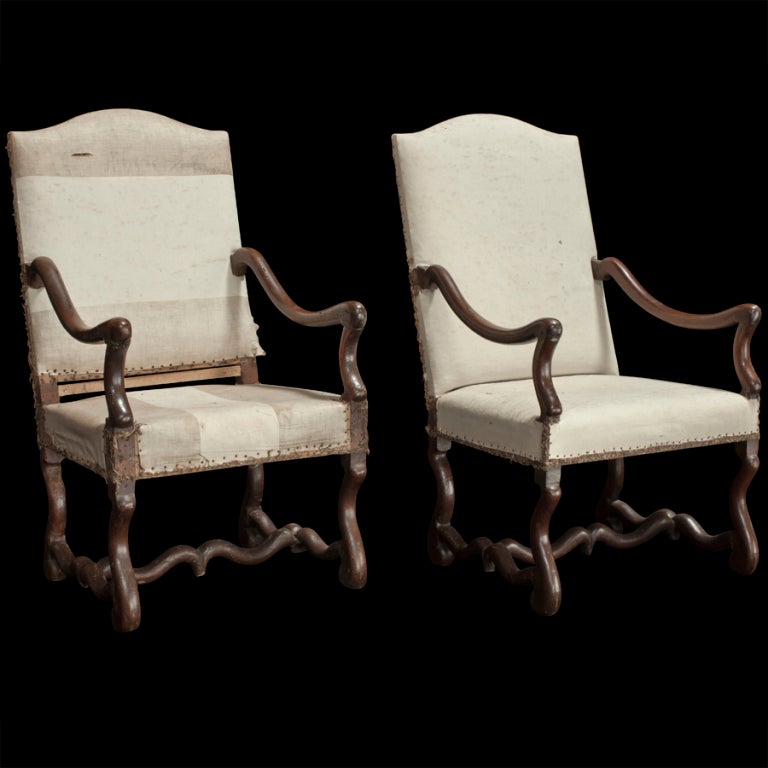 Pair of tall back armchairs stripped down to original grey lining with unusual stretchers and hand carved arms