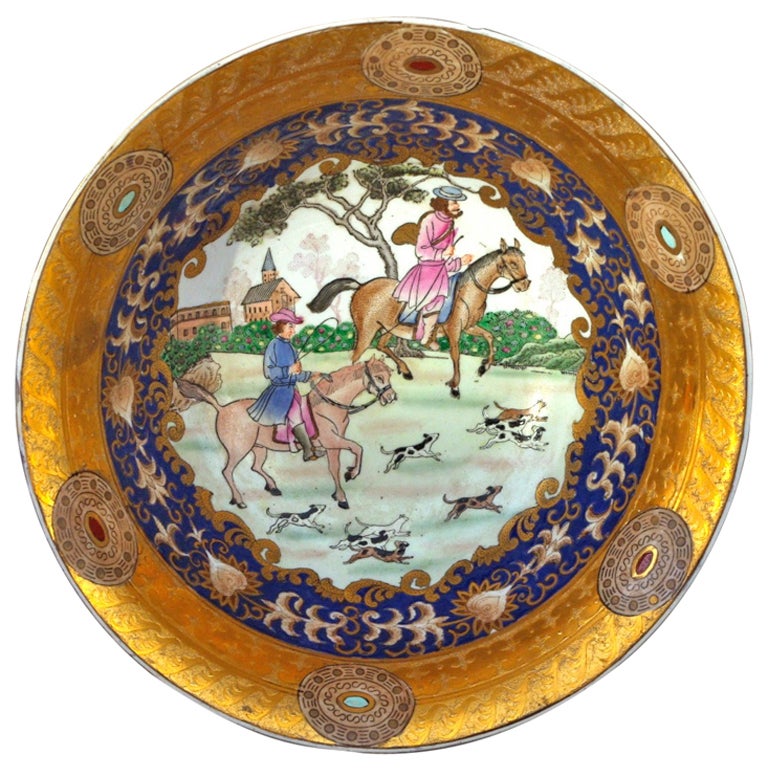 Flared porcelain bowl. Decorated by countryside scenes with hunting horse riders and their dogs. White-background scenes encircled in a vegetal frieze in blue and gold. In the inside, the gold side is highlighted with medallions.
Marked under the