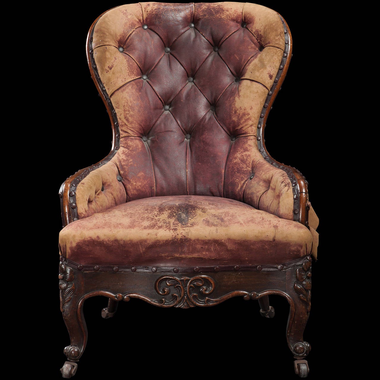 Tufted spoon-back chair with solid walnut from and ornately carved legs on original castors.