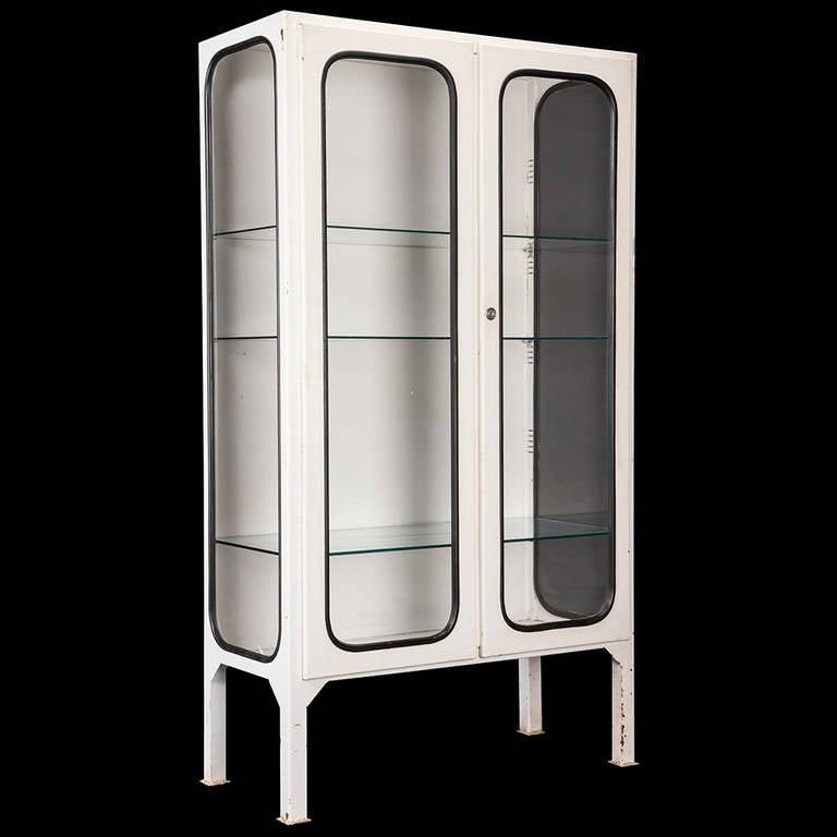 Steel medical cabinet with original white paint, and glass panels sealed in black rubber.

The first cabinet is 39.25