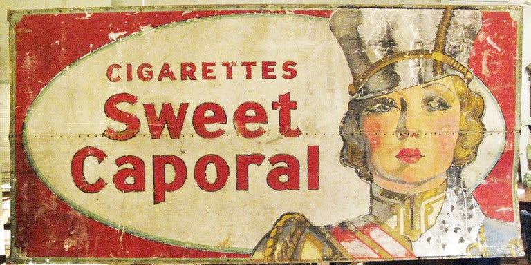 an amazing very large antique metal trade sign for sweet caporal cigarettes. absolutely beautiful design with a 40's woman in a majorette's coat and hat - great detailing on her outfit and face and expression. good overall condition with age