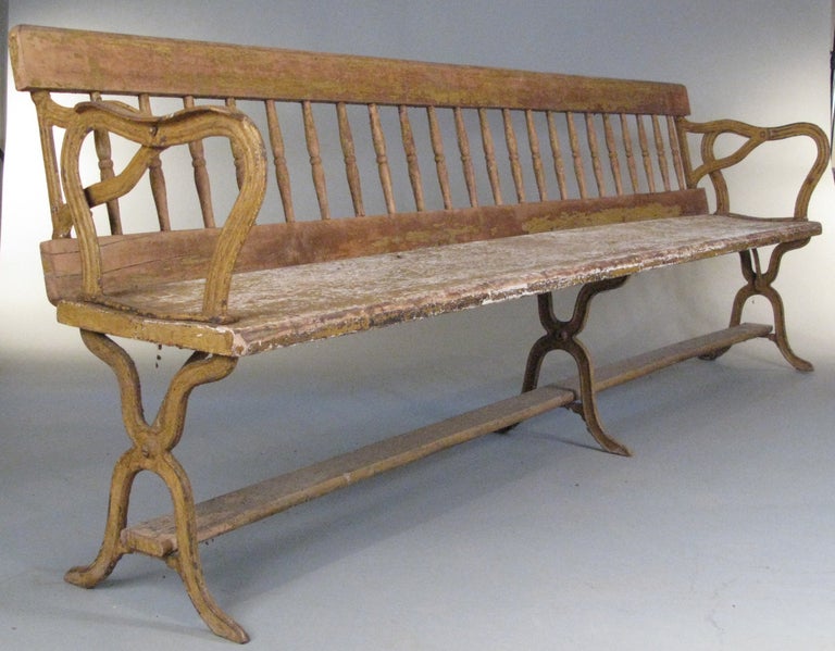 an antique reversible railway bench, used on railroad platforms in the 19th century, the back has cast iron mounts and is easily pivoted up over the top so the bench can be used to sit on either side depending upon which side the train was