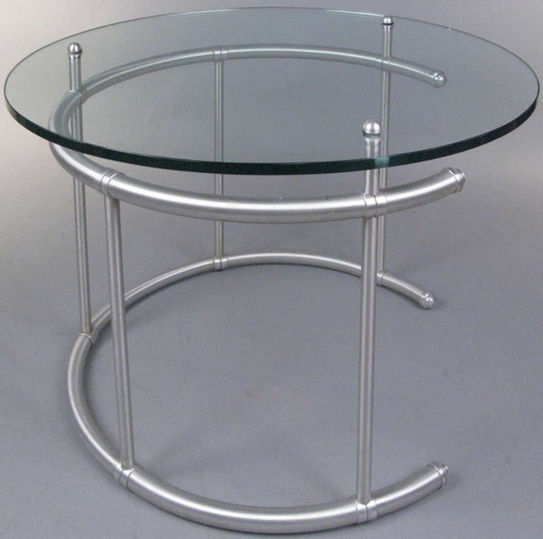 an outstanding rare 1930's occasional table by Warren Mcarthur, having a brushed aluminum base in an open circular form, with vertical bars supporting a round glass top. an elegant table with beautiful details.