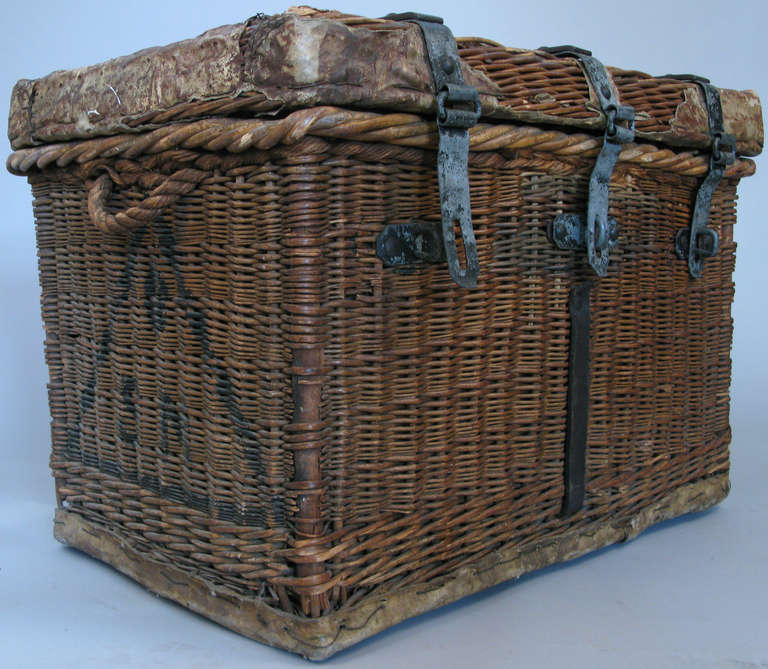 a large antique woven rattan trunk with cast iron straps and hinges, lined in tin, with wooden sled base with iron rollers. excellent condition.