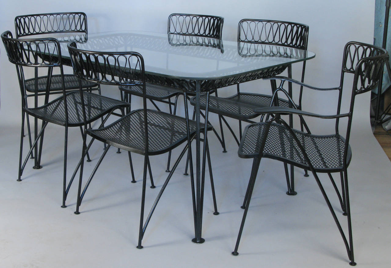 A Classic and iconic Salterini dining set from the 1950s. Designed by Maurizio Tempestini, it is one of their most recognizable designs, with heavy and well made wrought iron frames and his dynamic wrought iron ribbon detail in the curved backs of