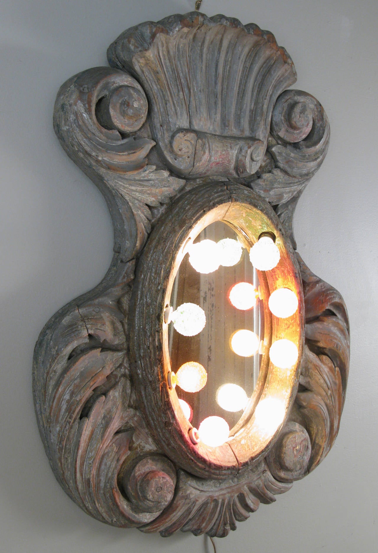 A wonderful heavily carved antique carousel mirror, with a border of lights and some hints of the original painted finish. Restored and rewired, it is a unique and original beauty!