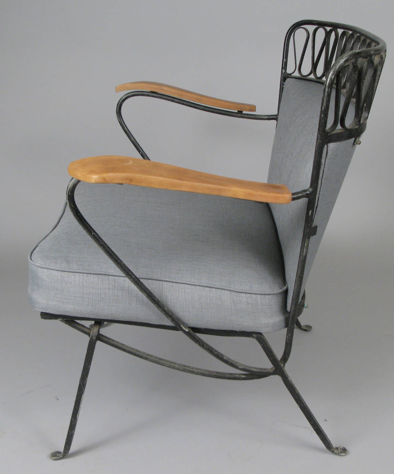 A rare and beautiful iron lounge chair designed by Maurizio Tempestini for Salterini, circa 1950. With the classic and iconic ribbon detailing and an upholstered seat and back and wood arms.