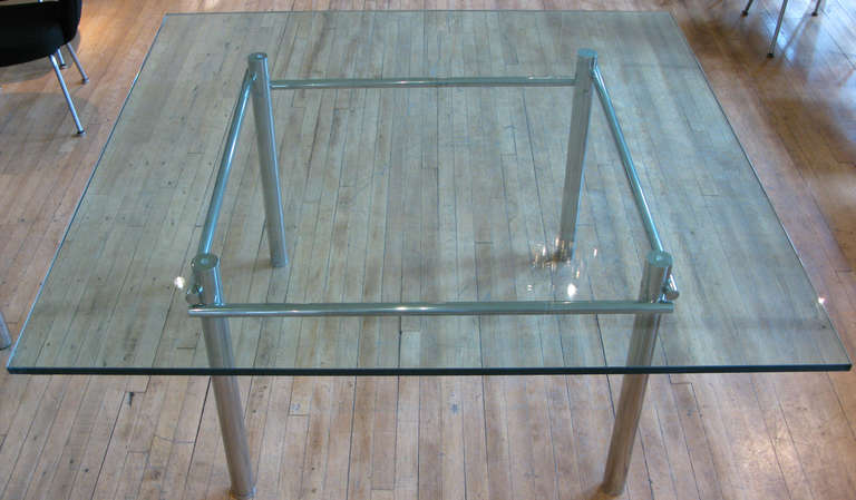 A striking modern dining table with a very heavy and well-made base in polished stainless steel with adjustable feet and thick glass top. Spare and elegant design. Base is in mint condition, glass has some scratches.