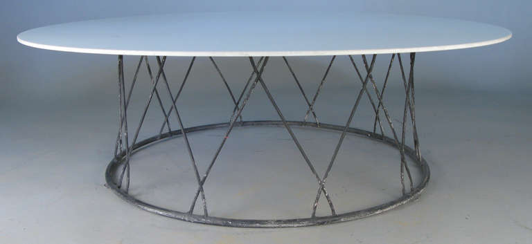 a very finely made and elegant 1950's cocktail table by Salterini, with a wrought iron base with crossed rods, and a round vitrolite (white glass) top. the top does have a ship in one spot as pictured, primarily underneath the top. there is also a