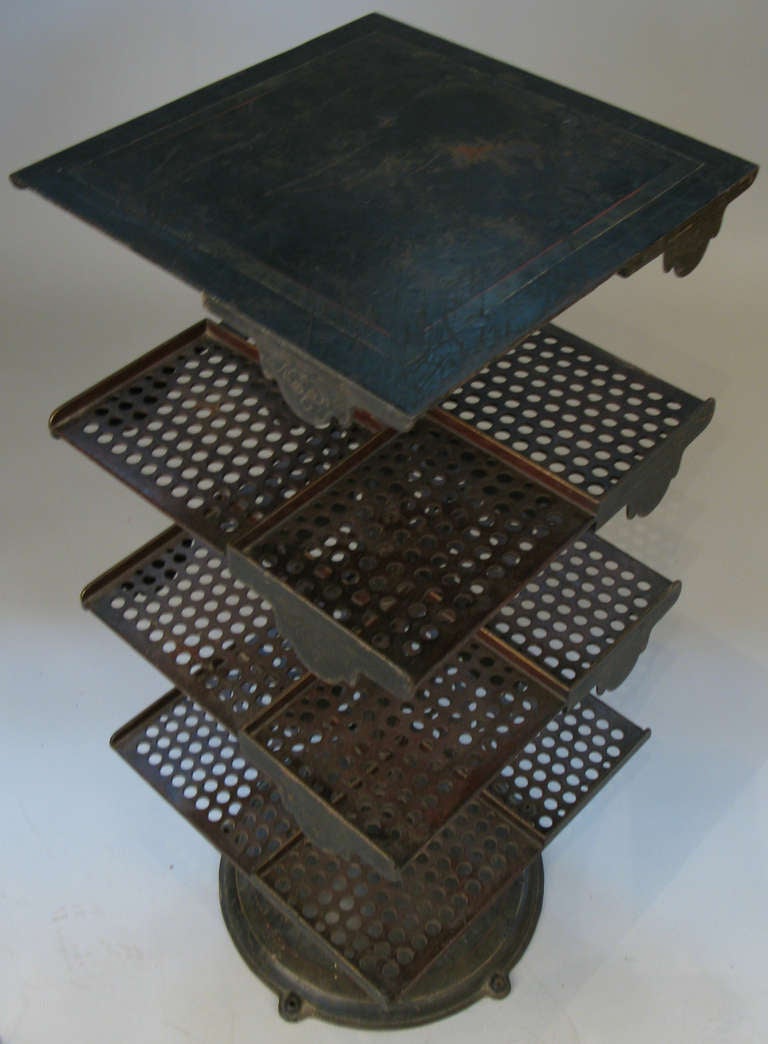 a very unique antique industrial cast iron revolving adjustable bookstand. a round cast iron base supports a center stem with 3 cast iron perforated and divided shelves, all height adjustable, and a solid cast iron top. in original ebony finish with