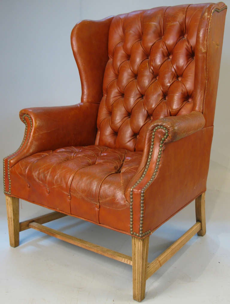 an extremely handsome and comfortable vintage wing chair in button tufted leather. generous proportions and beautiful patina on the caramel colored leather upholstery. raised on a natural oak base.