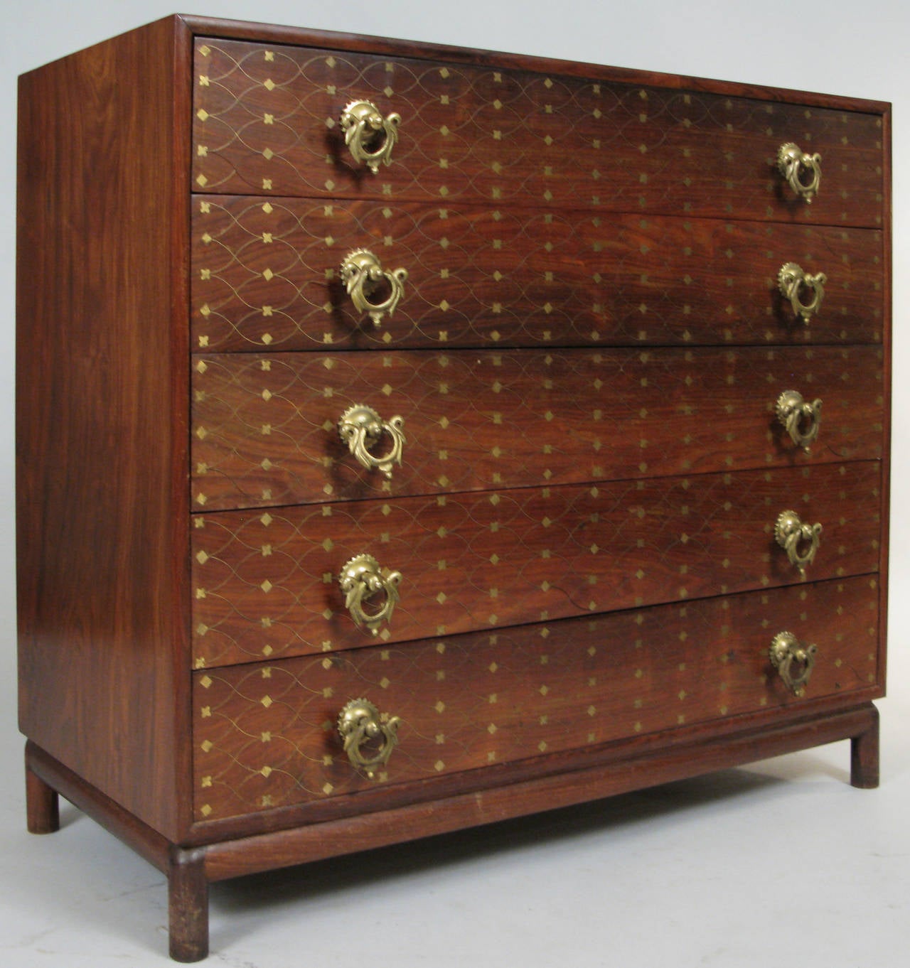 An outstanding five-drawer chest of drawers in solid rosewood, with the most wonderful inlaid brass details on the drawer fronts with a thin crossover pattern in brass, with diamond details also inlaid in brass. Absolutely beautiful details in this