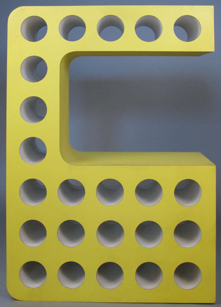 a very unique and dynamic vintage 1970's Pop Art wine bottle rack in bright yellow laminate, with white interiors. in the shape of a stylized C, with storage for 23 bottles.