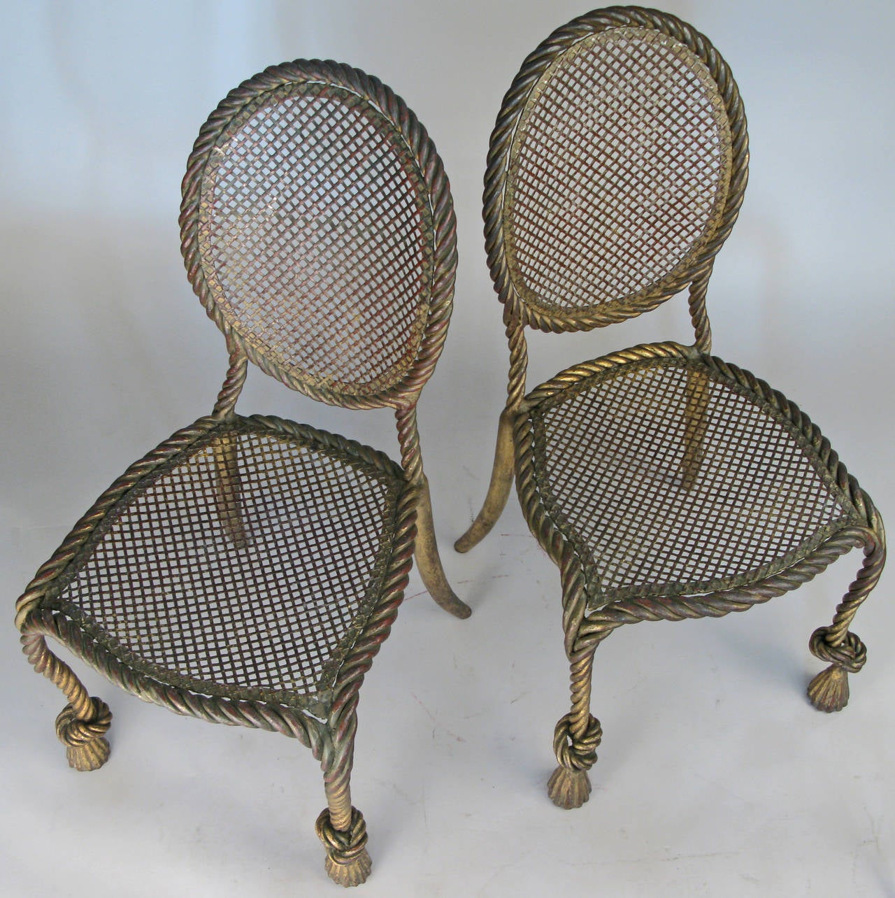 A pair of very well-made and elegant Classic 1950s Italian chairs with heavy frames made in the form of twisted rope with tassel front feet. Finished in their original Italian gilt gold over red. Finish has worn into a beautiful dark patina. Truly