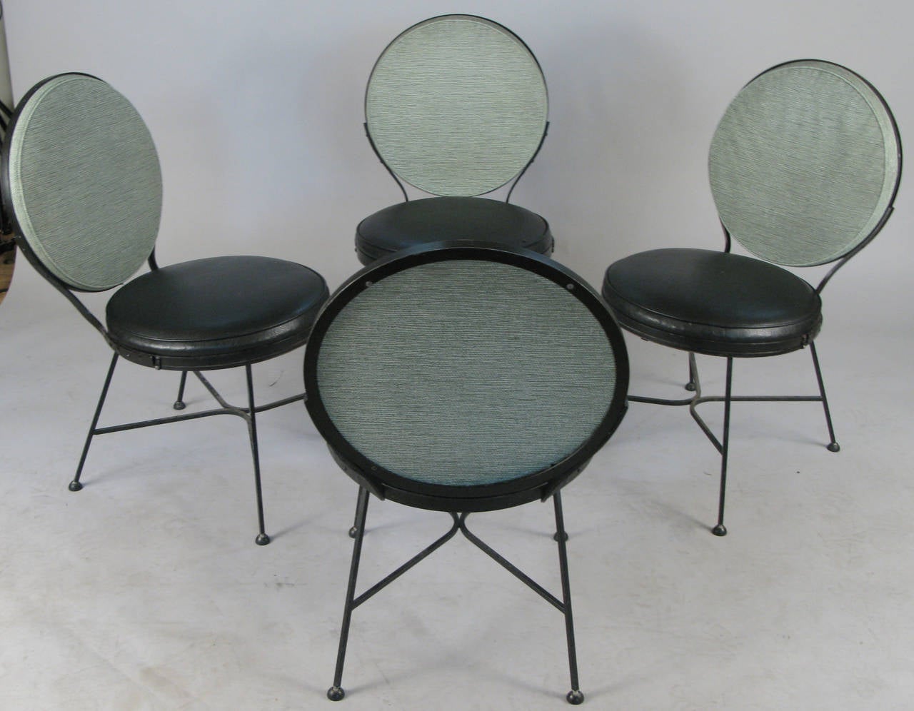 A set of four well-made and beautiful 1950s modern chairs by Troy Sunshade, with wrought iron frames and the original vinyl upholstery in black seats and pale mint green backs. Great design in excellent condition.