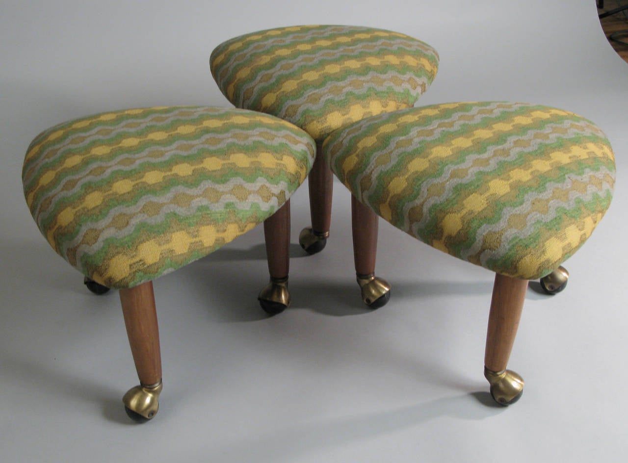 a matched set of three vintage 1960's triangle upholstered stools designed by Adrian Pearsall for Craft Associates, with tapered walnut legs and brass casters.
