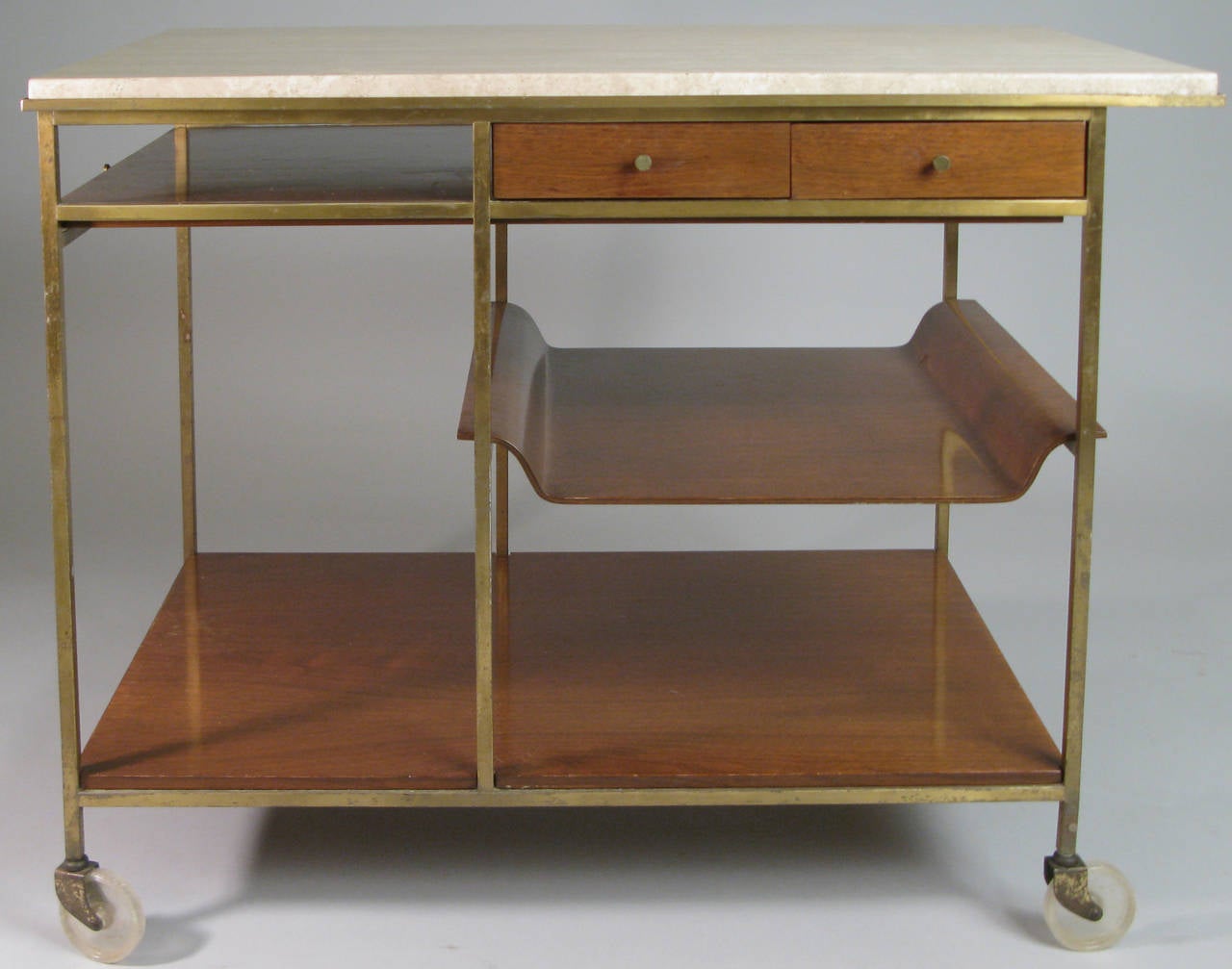 a classic 1950's rolling bar cart by Paul McCobb for Calvin with a sliding shelf, travertine top, two drawers and a removable serving tray which doubles as a shelf.