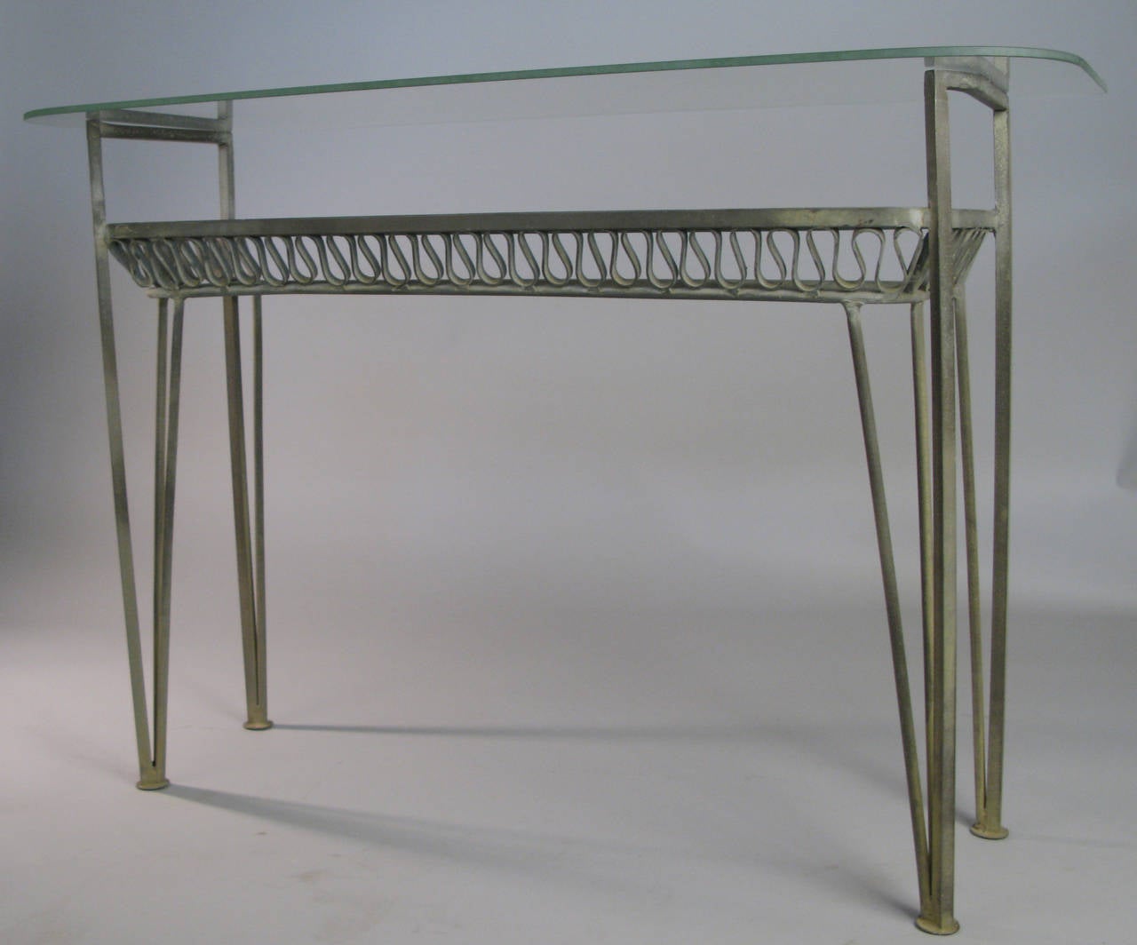 A rare 1950s wrought iron double shelf console table designed by Maurizio Tempestini for Salterini, with two long glass shelves and Tempestini's signature iron ribbon design under the lower shelf. Wonderful original patina.