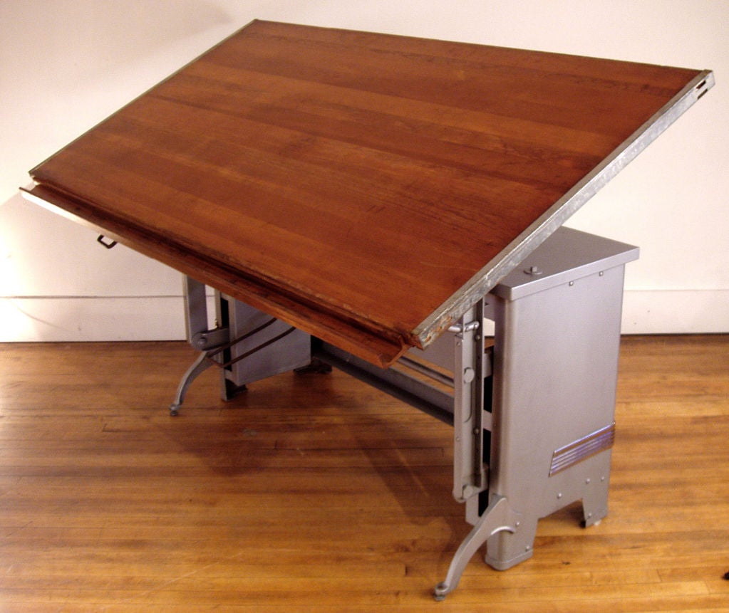 a very nice large antique adjustable drafting table by Hamilton. This table is easily adjustable for tilt angle of the top and height as well. having a coated steel base and wood top with a beautiful patina. excellent condition.