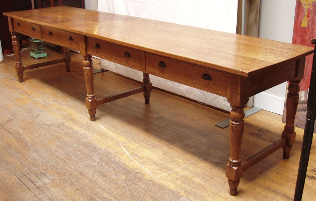 a very nice large standing oak mercantile table. thick oak top with 4 drawers raised on six turned oak legs with stretchers. wonderful patina. perfect as a desk or library table or as a display table in a retail shop.