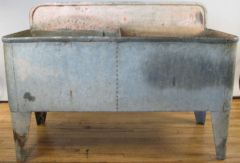 an early 20th century french farmhouse sink in galvanized steel with a raised backsplash.