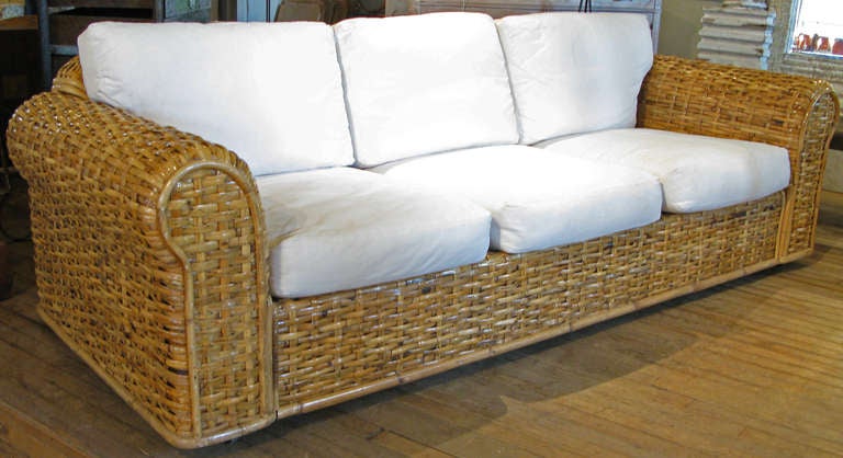 a beautiful and gracious large sofa by Ralph Lauren Home, in large scale woven rattan. Extremely well made and very comfortable, with cushions upholstered in white cotton canvas upholstery. great details and in excellent condition.