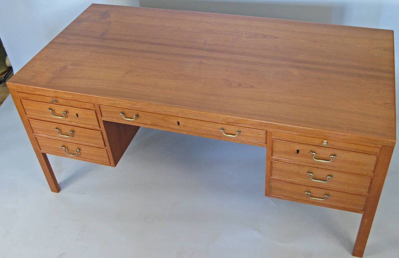 A very handsome vintage 1960s Danish teak desk designed by Ole Wanscher, with seven drawers in the front, a pair of slide out work surfaces, and a pair of locking cubbies on the back as well as a center bookcase with an adjustable shelf. Elegant